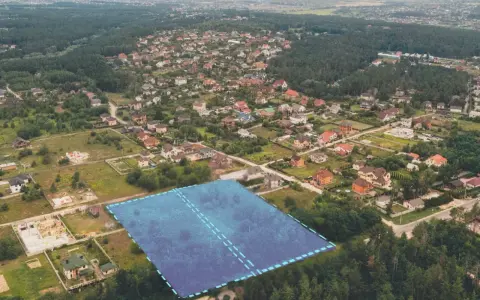 Działki bez planu ogólnego gminy będą niesprzedawalne od lipca 2026. Aerial view of suburban housing development with a highlighted plot of land.