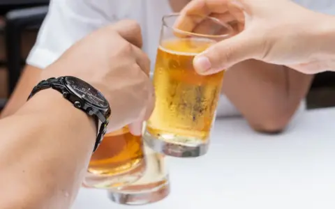 Dwie osoby wznoszą toast piwem. Pytanie: czy chory na raka może pić alkohol?