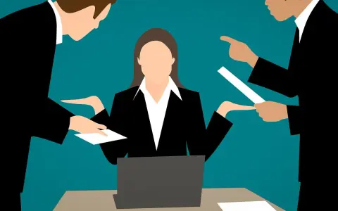 Kobieta przy biurku z laptopem, otoczona przez dwóch mężczyzn, którzy wskazują na dokumenty. Wygląda na to, że jest to sytuacja z zażaleniem po angielsku.