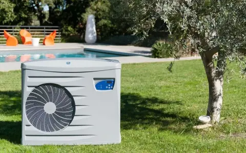 Pompe à chaleur pour piscine, élément clé d'un schéma de filtration performant, installée sur une pelouse verdoyante près d'une piscine.