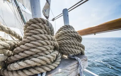 Gros cordages enroulés sur un voilier, prêts pour le moteur fonctionnement. La mer bleue et le ciel clair en arrière-plan.