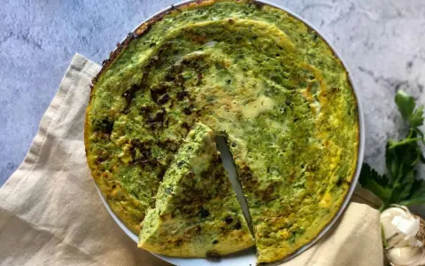 Frittata di zucchine in padella, dorata e profumata, con una fetta tagliata per mostrare la morbidezza interna.