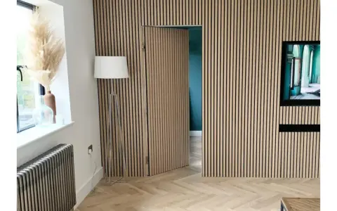 Una puerta oculta en una pared revestida de lamas de madera, una solución ingeniosa para como ocultar una puerta en una pared.