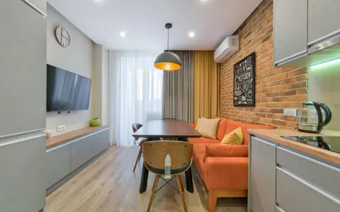 Idée pour aménager salon salle à manger 15m2 : canapé orange, table en bois, mur brique, cuisine moderne.