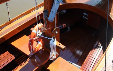 Le bois de bateau verni brille au soleil. Une bouée orange est accrochée, prête pour l'aventure.