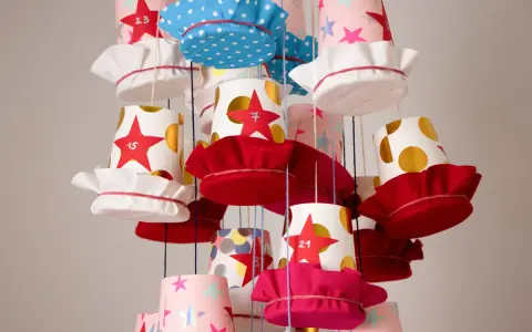 Bunte Becher mit Sternen und Punkten, die als Adventskalender becher basteln dienen. Jede Tasse hat eine Zahl und eine Stoffkappe.