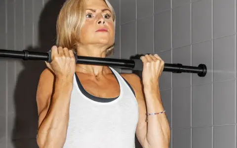 En kvinna med blont hår utför chin ups vid en stång.
