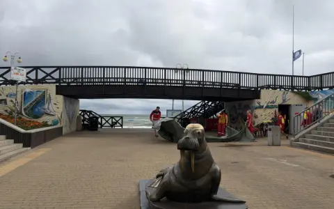 Pomnik foki i most nad plażą w Mielnie. Atrakcje dla turystów, ratownicy przygotowują sprzęt.
