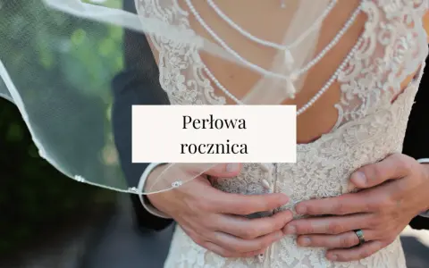Perłowa rocznica ślubu. Dłonie obejmujące suknię ślubną z koronki i pereł.