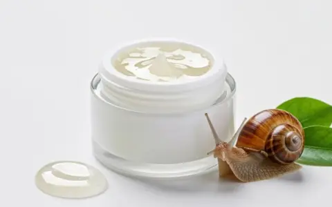 Ślimak obok słoiczka z kremem, symbolizującym naturalne składniki snailmed.