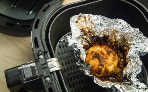 Ein gebackener Knoblauch in Alufolie in einem Airfryer. Ist Airfryer gesund? Ja, mit wenig Öl.