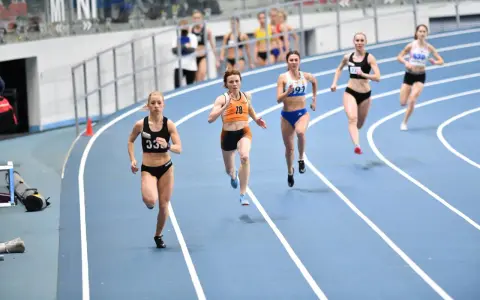 Aneta Lemiesz biegnie w zawodach lekkoatletycznych, walcząc o zwycięstwo na bieżni.