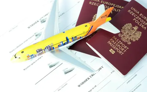 Model samolotu leży na dokumentach i dwóch paszportach. Widać fragmenty wniosków urlopowych i okładki paszportów, które pokazują, jak wygląda paszport.
