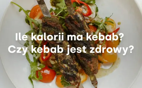 Dwa szaszłyki z mięsem i warzywami na talerzu. Tekst pyta: "Ile kalorii ma kebab? Czy kebab jest zdrowy?".