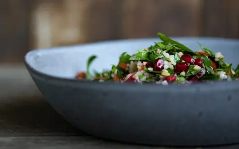 Frischer Tabouleh-Salat mit Granatapfelkernen in einer grauen Schüssel. Ein köstliches Rezept für den Sommer.