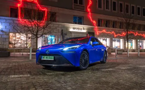 Niebieska Toyota Mirai na nocnej ulicy z neonowym oświetleniem.
