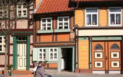 Fachwerkhäuser in Wernigerode, ein Ort voller geheimtipps. Zwei Personen sitzen auf einer Bank vor bunten Häusern.