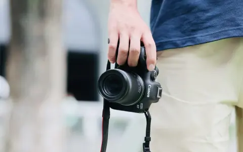 Dłoń trzyma aparat Canon EOS R7, gotowy do uchwycenia chwili. Jego matryca w aparacie zapewni doskonałą jakość zdjęć.