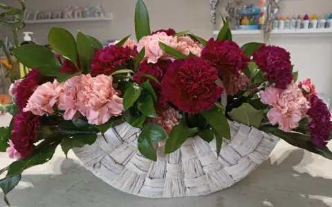Piękne kompozycje z goździków w koszu. Różowe i bordowe kwiaty z zielonymi liśćmi tworzą elegancką całość.