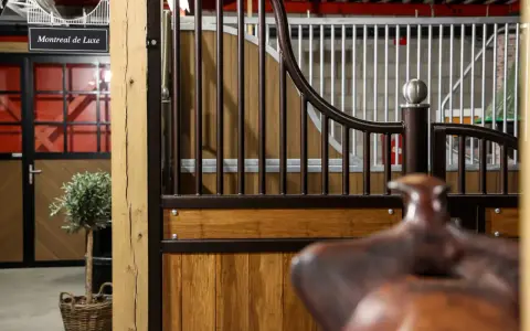 Une écurie de luxe avec des portes en bois, des barreaux en métal et un signe "Montreal de Luxe".