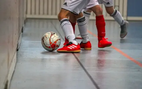 Piłka do futsalu na hali, obok butów zawodników. Tak, w turfy można grać na hali, to właśnie futsal!