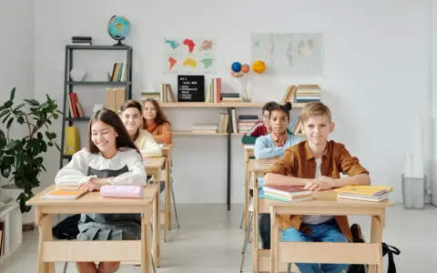 Uczniowie siedzą w ławkach w klasie, która wygląda jak szkoła średnia w Niemczech.