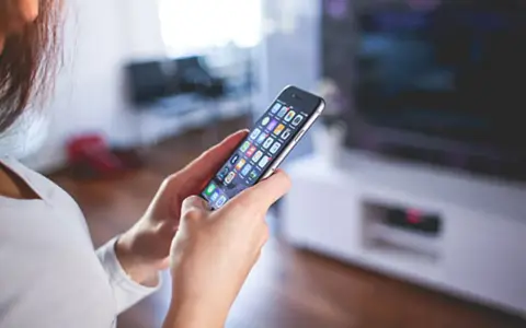 Kobieta trzyma w dłoniach iPhone A1586, przeglądając aplikacje.