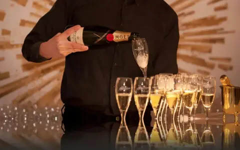 Kelner nalewa szampan Moët & Chandon do kieliszków, przygotowując się do wesela.