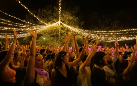 Gente disfrutando en el festival Ewan Salinas bajo un cielo de luces.