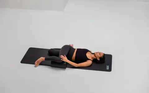 Frau mobilisiert mit Foam Roller die ISG-Region in Rückenlage.