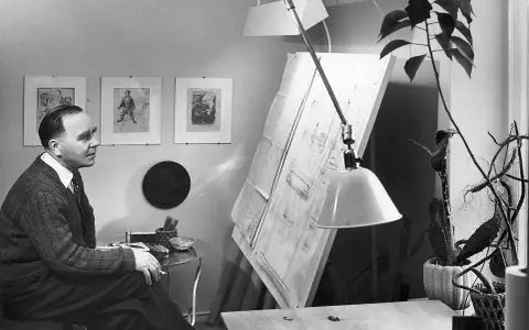 Paavo Tynell sitter vid sitt ritbord, omgiven av sina skisser och en stor ritning.