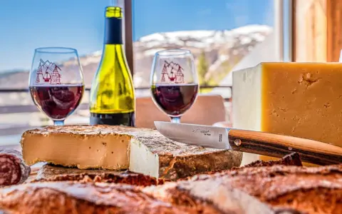 Dégustation de fromages et vin rouge, un aperçu de la gastronomie auvergnate avec vue sur les montagnes enneigées.
