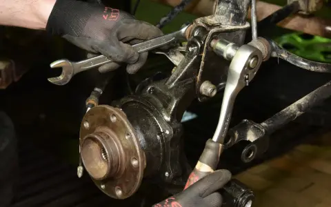Mechanik wymienia łożysko w Audi A3 8P przód, używając kluczy do demontażu elementów zawieszenia.