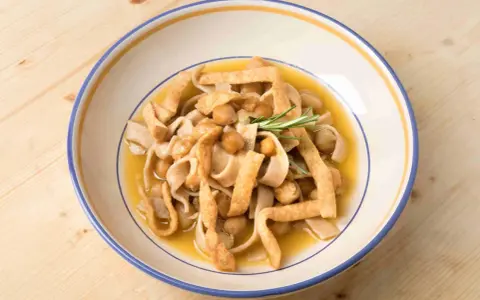 Piatto di ciceri e tria, pasta fresca con ceci e croccanti straccetti fritti, guarnito con rosmarino.