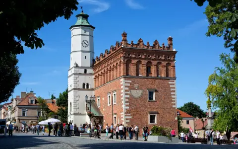 Ratusz w Sandomierzu z zegarem i zegarem słonecznym. Spacerujący ludzie na rynku, ciekawe miejsca Sandomierza.
