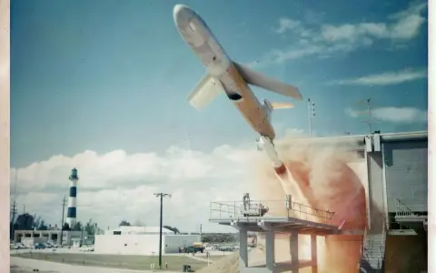 Rakete startet von Plattform, Rauch steigt auf. Ein Leuchtturm im Hintergrund. Eine Szene, die an die Kubakrise erinnert, zusammenfassend.