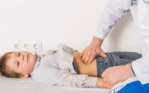 Médico examina el abdomen de un niño con posible gastroenteritis.