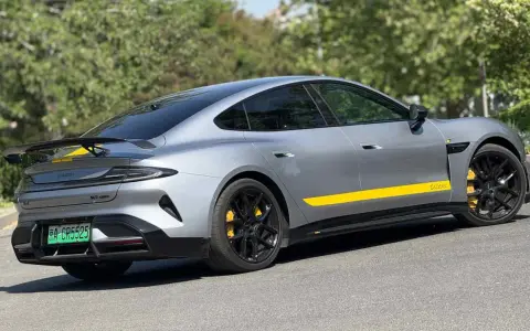 Silbernes Xiaomi Auto mit gelben Akzenten und Spoiler, das auf einer Straße parkt.