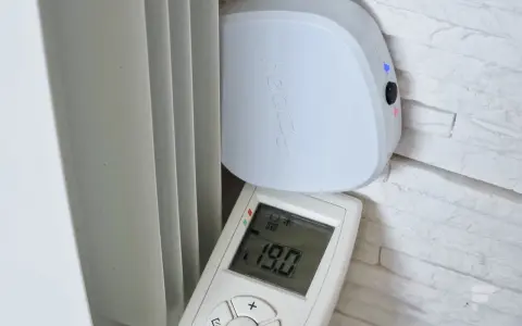 Schéma branchement thermostat chauffage électrique : un boîtier blanc "heatzy" et une télécommande affichant 19.0°C, près d'un radiateur.