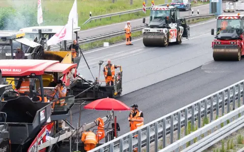 Arbeiter legen auf der ADAC A2 mit Maschinen und Walzen neuen Asphalt.