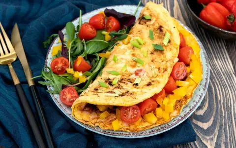 Pyszny omlet fit z pomidorkami i papryką, podany z sałatką. Idealny na zdrowe śniadanie.