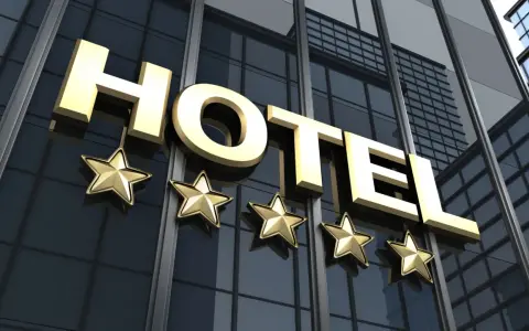 Złote litery "HOTEL" i pięć gwiazdek na nowoczesnym budynku. Spełnia hotel 4 gwiazdki wymagania luksusu i komfortu.