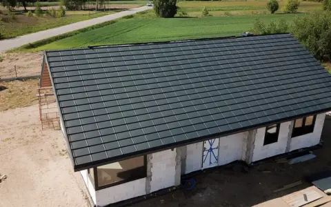 Nowy dom w budowie z ciemnoszarym dachem, widok z góry.