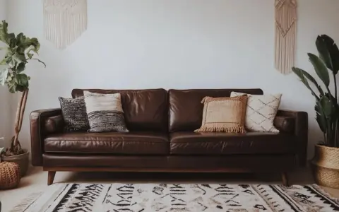Un canapé marron en cuir, décoré de coussins texturés. Idéal pour savoir quelle couleur associer avec un canapé marron, avec des plantes vertes et un tapis ethnique.