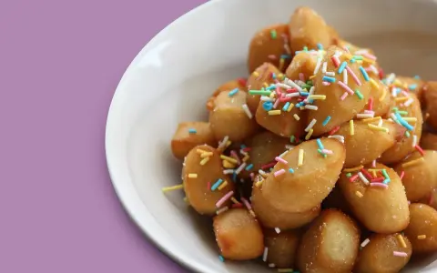 Un piatto di dolci tipici pugliesi, piccole palline dorate cosparse di zuccherini colorati, invitano a un assaggio di tradizione.