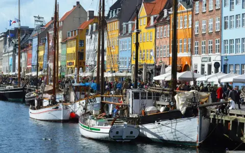 Colorful buildings line a canal in Copenhagen, with boats docked and people enjoying the waterfront. A perfect scene for exploring things to do in Denmark.