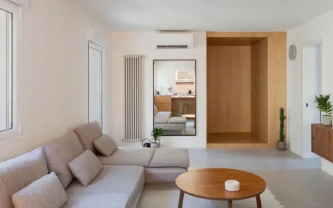 Salon épuré avec canapé modulable, table basse en bois et un coin boisé rappelant une maison style japonais en France.