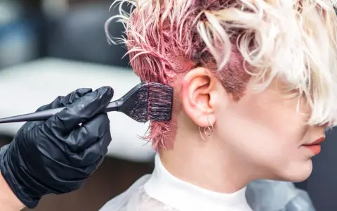 Aplicando tinte rosa en el cabello. Si te manchas, aprende como quitar el tinte de la piel.