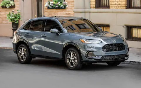 Elegancki, szary SUV Honda HR-V stoi na ulicy przed budynkiem z cegły.