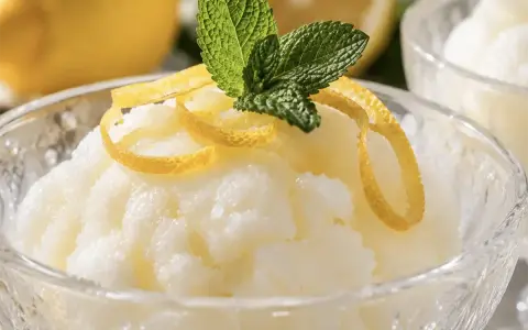 Sorbetto al limone senza albume, fresco e profumato, guarnito con scorzette di limone e foglioline di menta.